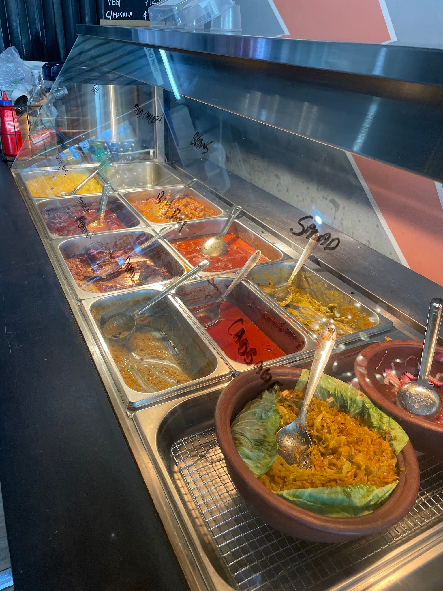 Green Cabin food service counter with bain-marie trays of curries, dhal, sambal and coconut