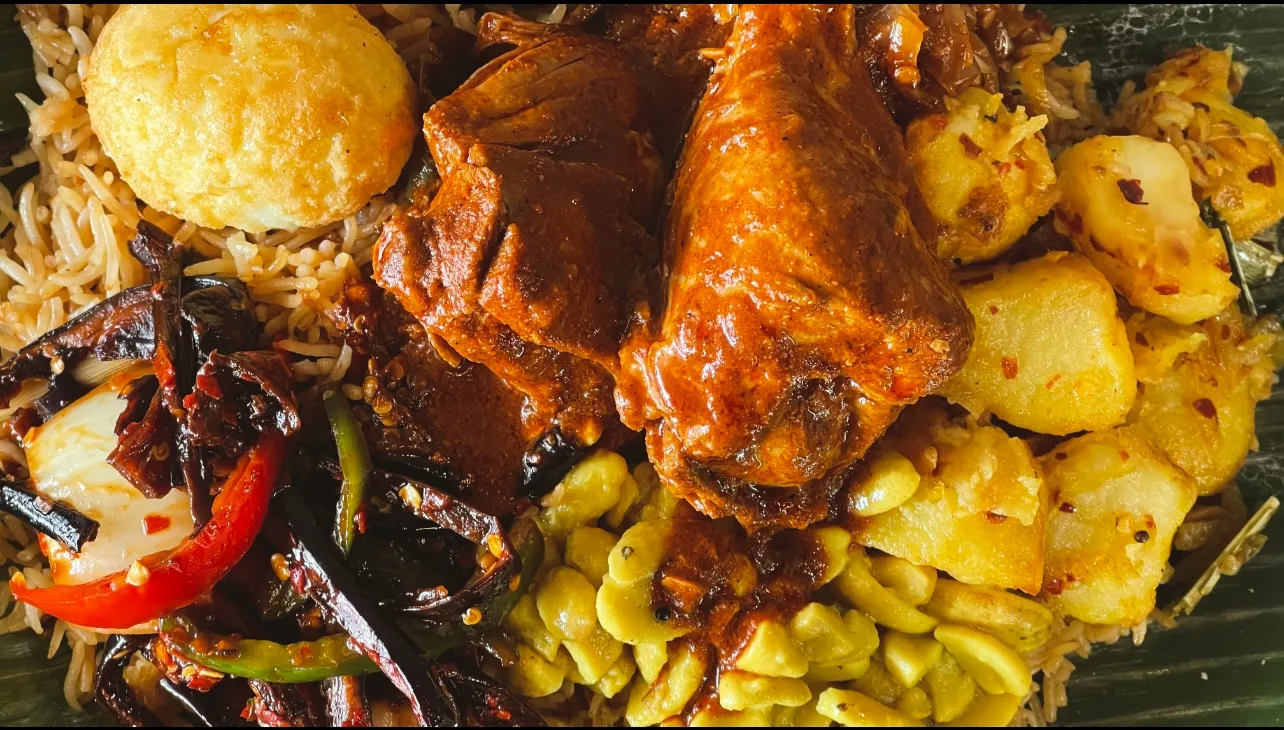Biryani on banana leaf with chicken drumstick, roasted cashews, capsicum and potato in warm amber light
