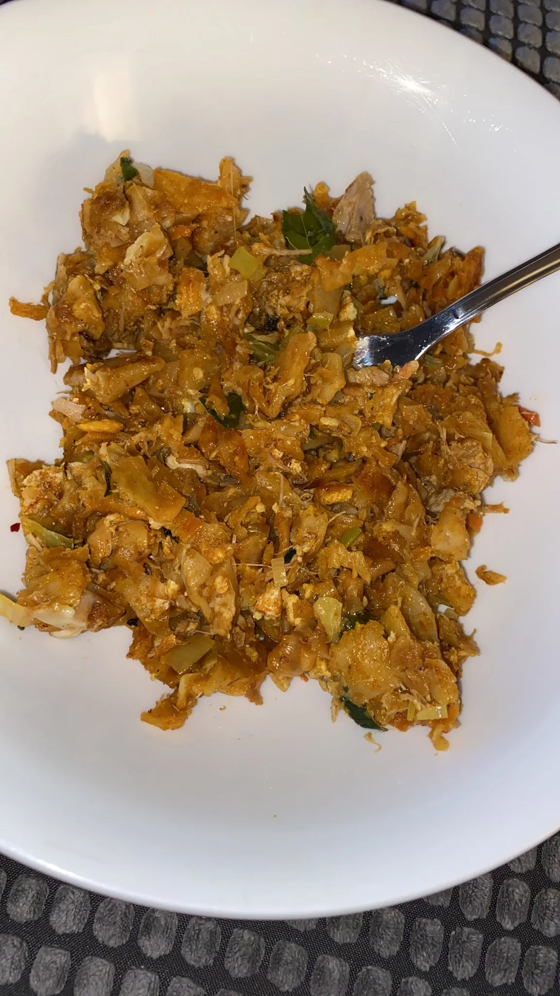 Kothu roti in white bowl, shredded flatbread stir-fried with vegetables and spices