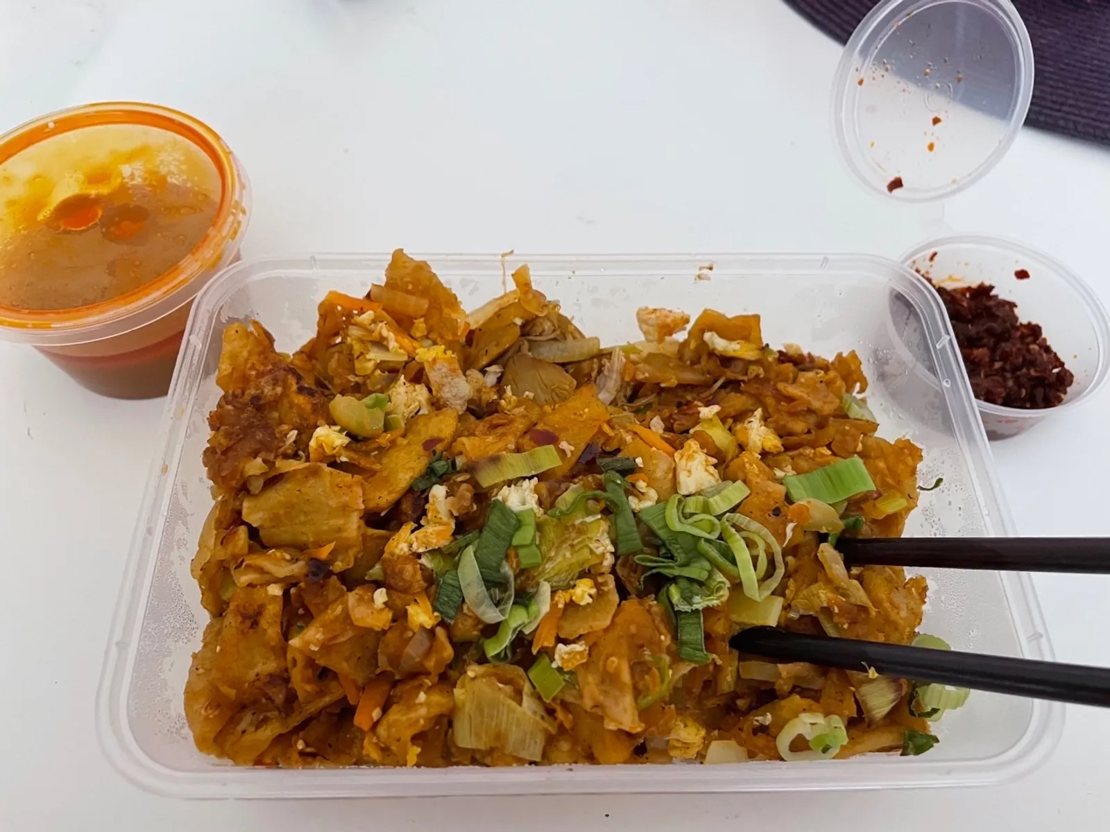 Kothu roti takeaway container with dipping sauce and chilli flakes