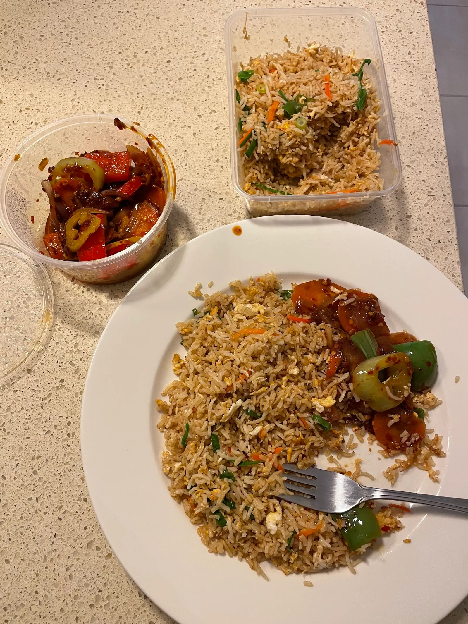 Fried rice on white plate with sweet capsicum topping, takeaway container and chilli relish